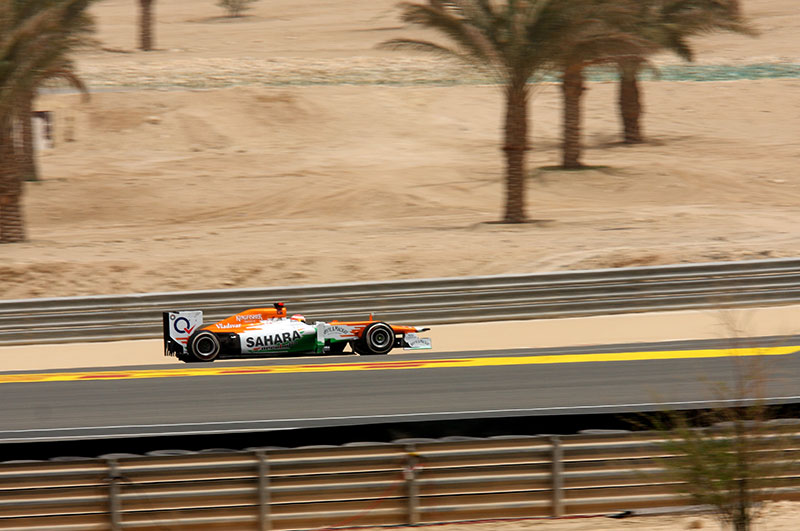 single f1 racing car on the track with palm trees and desert in the background