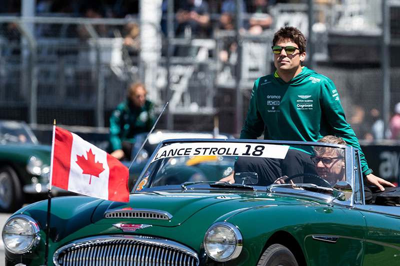 lance stroll sitting up top of a vintage aston martin in green