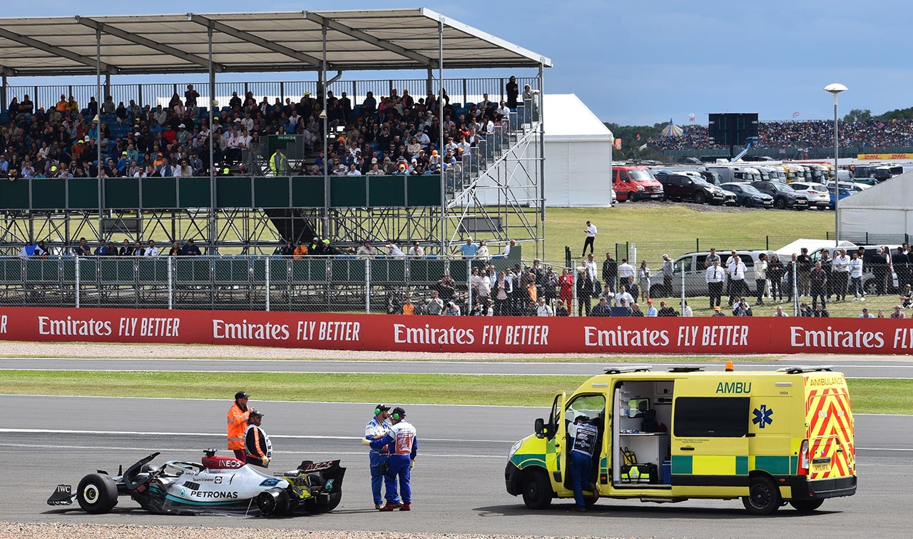 ambulance and f1 car with staff waiting, grandstancd in view