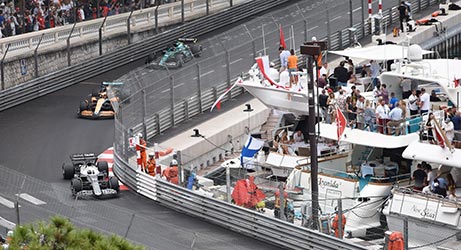 f1 cars racing in monaco past some luxury yachts
