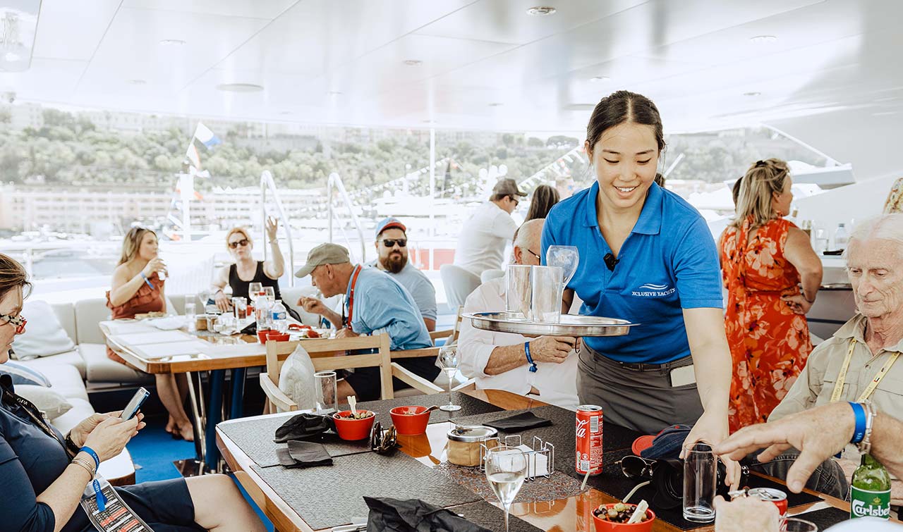 waitress serving guests at a table on a luxury yacht