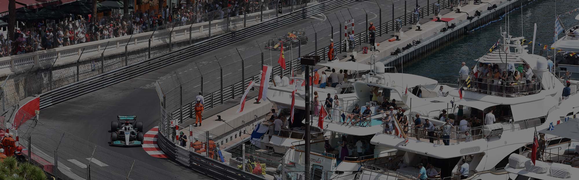 grand prix cars racing in monaco with spectators watching from luxury yachts