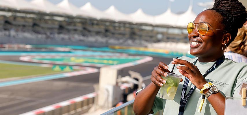 woman smiling with a drink and the track in the background