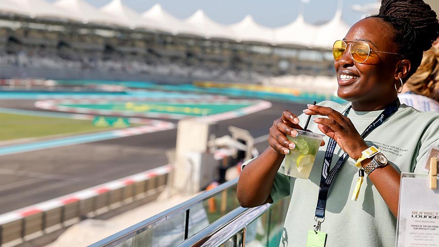 woman smiling with a drink and the track in the background