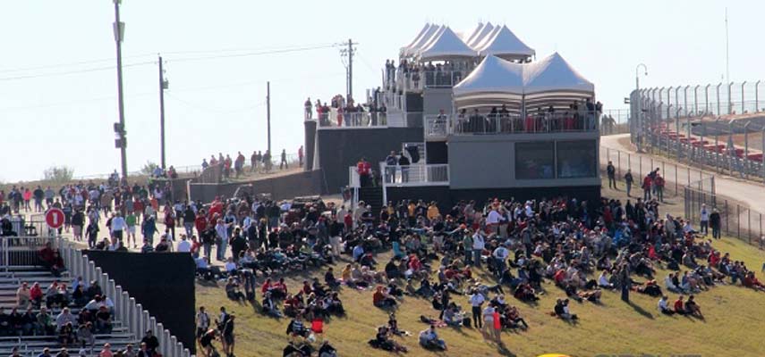 f1 fans watching the grand prix on a grass hill