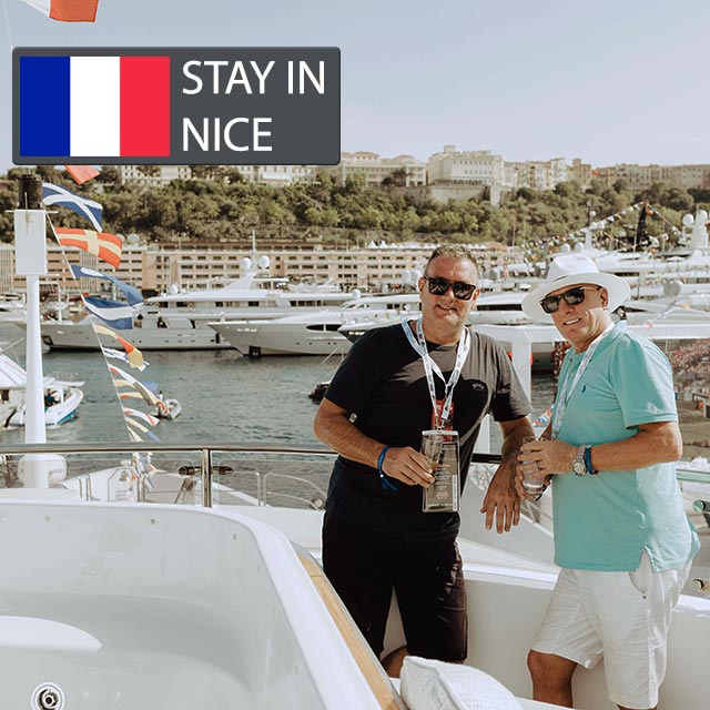 2 happy f1 fans standing on a yacht in the harbour of monaco