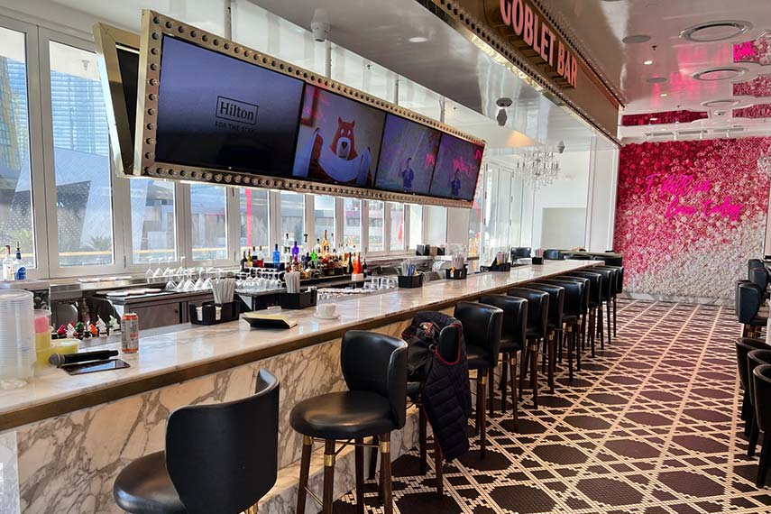 long tv screen with sections above the bar and bar stools