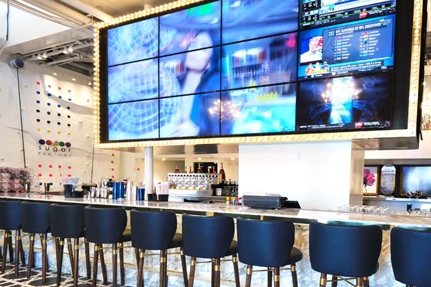 long bar with chairs and a huge TV screen