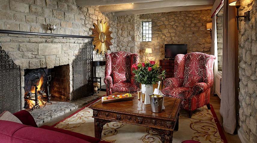 living room with stone walls, large sitting chairs, champagne on the table, wood fire burning away
