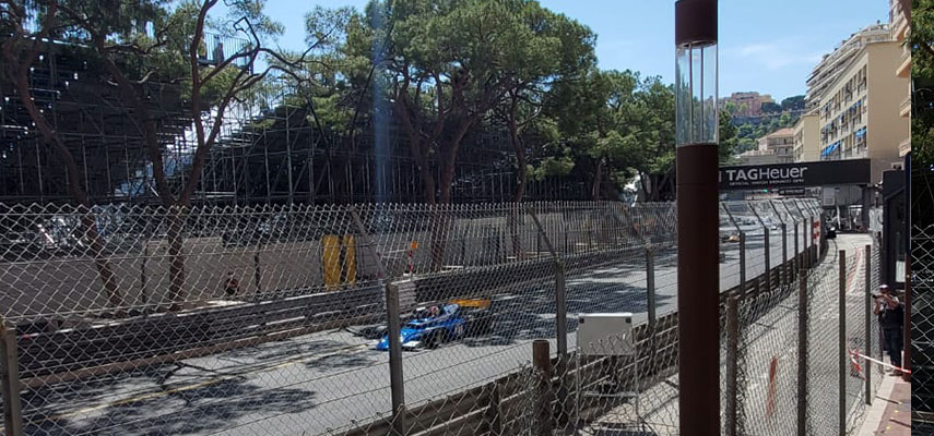 f1 car racing past, view through a fence