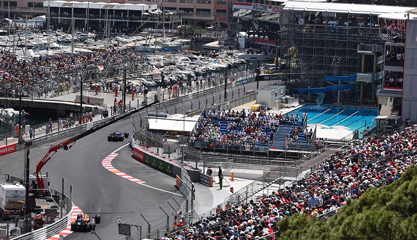 monaco gp f1 cars racing with views of the crowd, yachts and swimming pool