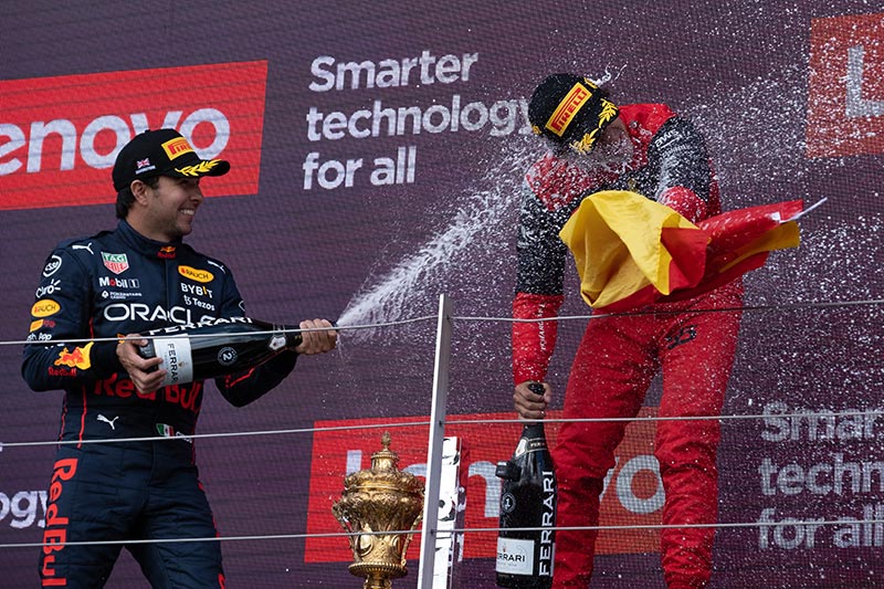 carlos sainz getting sprayed with champagne on the winners podium
