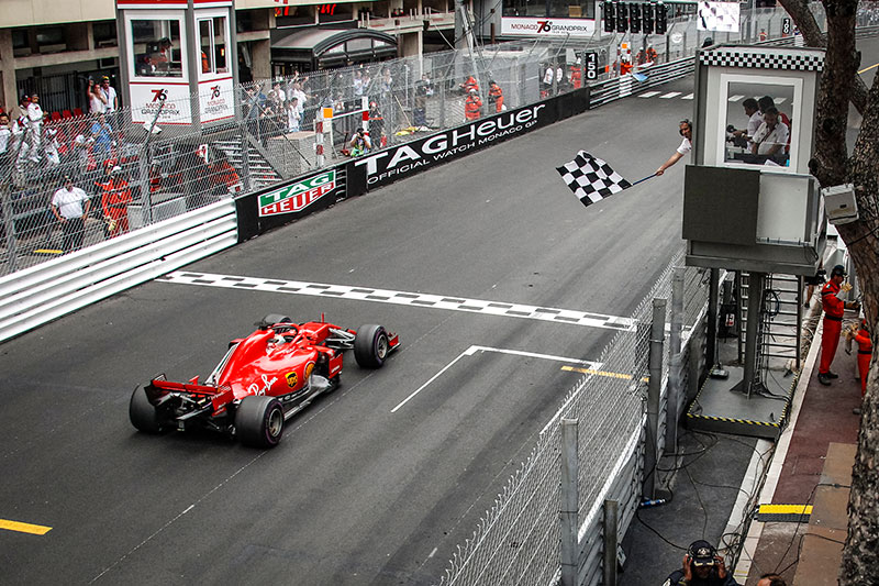 f1 car racing to the finish line and shows the chequered flag