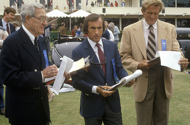 The Scottish race car driver Jackie Stewart, center, and other former racecar drivers judge classic cars at the 35th Annual Concours D' Elegance Competition, ca. 1985