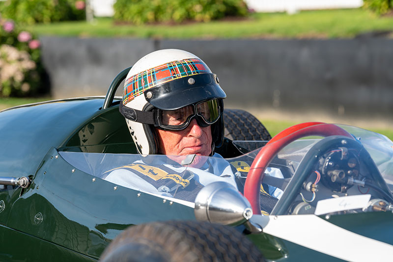 Goodwood, Sussex / UK - 14 Sept 2019: Sir Jackie Stewart, wearing his trademark tartan and white helmet, sits behind the red steering wheel of a classic race car at the annual vintage Revival event.