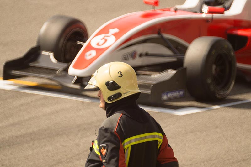 racing official in the foreground and an older f1 car
