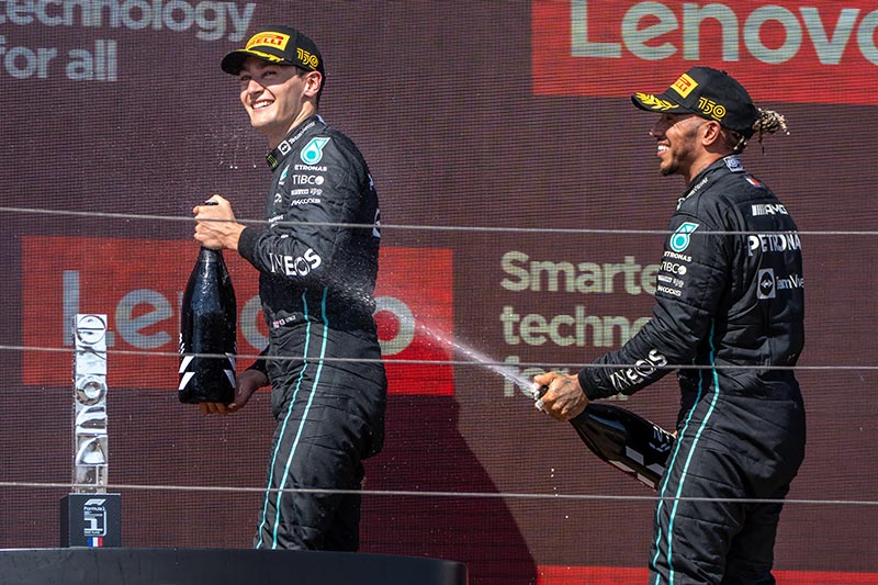 lewis hamilton and george russell celebrating on the podium with champagne