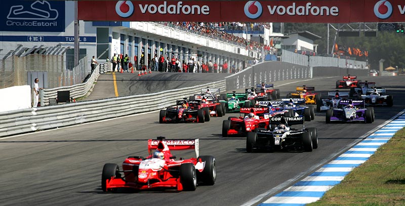 f1 cars racing down a straight at the portugal gp