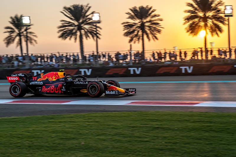 red bull car racing in abu dhabi, palm trees in the background with the setting sun