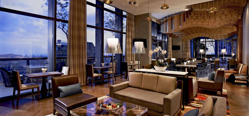 hotel lounge with tables, chairs and couches, views of the city from the window