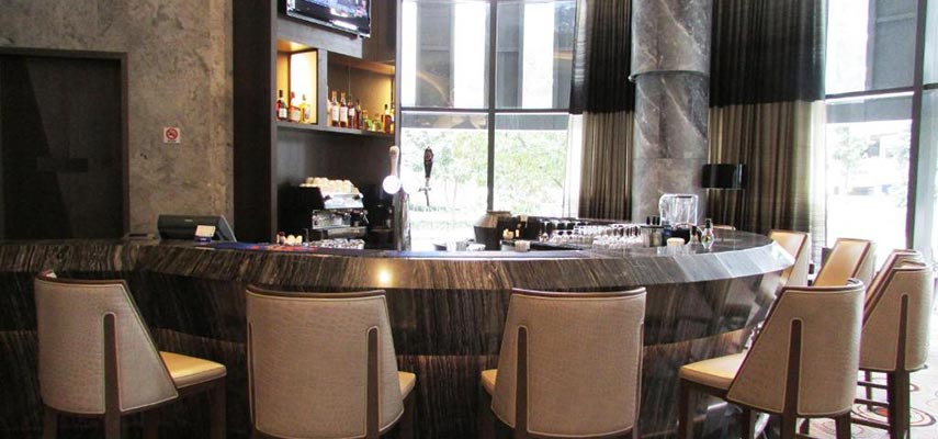 cosy hotel bar with bar stools and a TV above bar