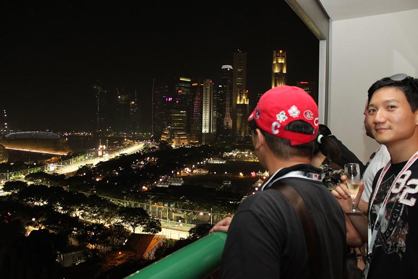 guests on a balcony looking over the city of singapore at night