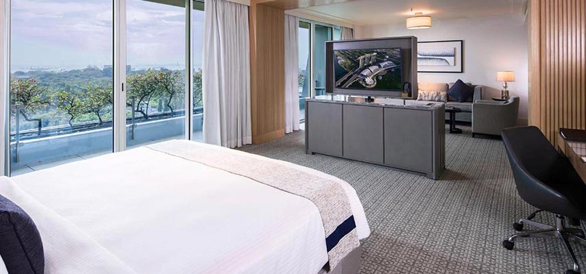 large hotel bedroom with TV chair and views outside